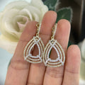 Woman holding Yellow and White gold three row pear shape drop earrings.