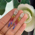 Woman holding diamond and multi colored sapphire drop earrings. (etsy image id: 6707302176)