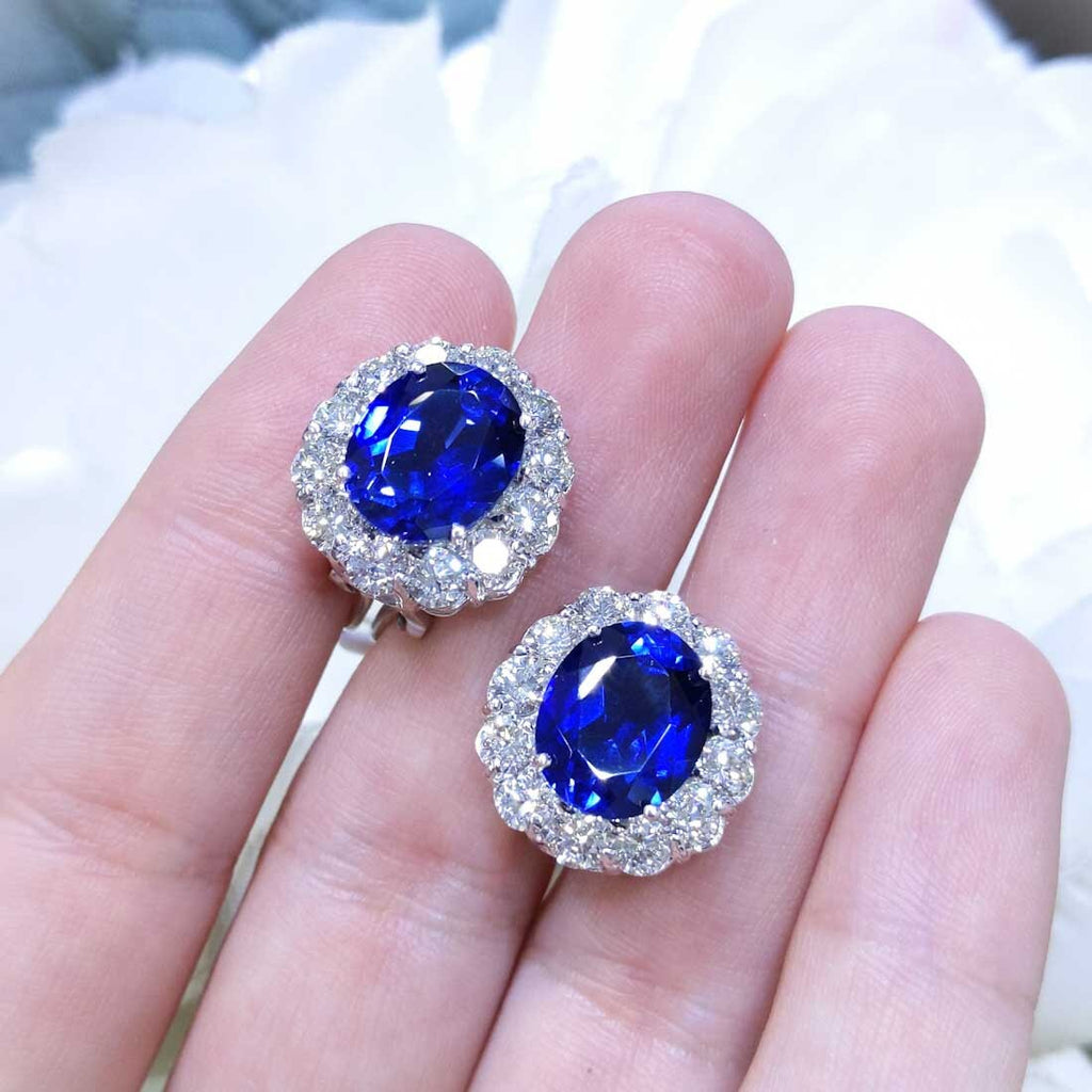 Woman holding Lab Blue Sapphire clip on stud earrings set in a halo setting surrounded by natural diamonds. (etsy image id: 6709995140)