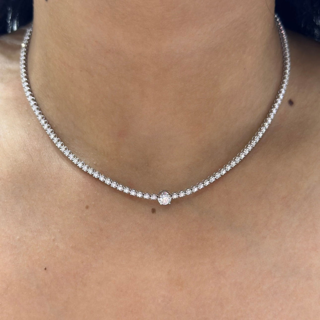 Woman wearing a diamond tennis necklace with larger carat stone in the center. (etsy image id: 6712827626)