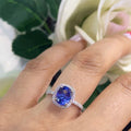 woman wearing a white gold ring featuring a center tanzanite stone set in a halo setting. (etsy image id: 6728277880)