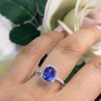 woman wearing a white gold ring featuring a center tanzanite stone set in a halo setting. (etsy image id: 6728277880)