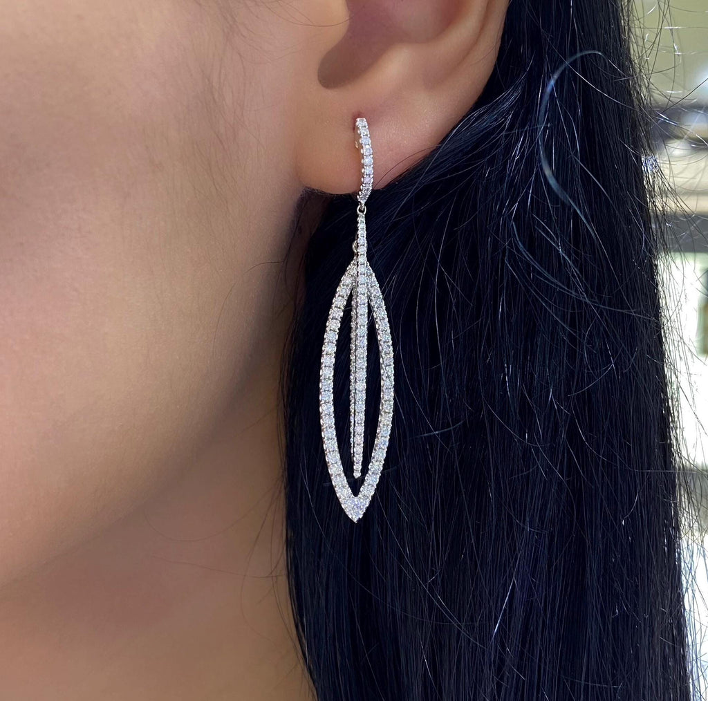 Woman wearing white gold elongated double oval shaped dangling diamond earrings. (etsy image id: 6740773018)