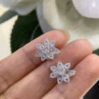 Woman holding white gold diamond cluster flower stud earrings. (etsy image id: 6741413570)