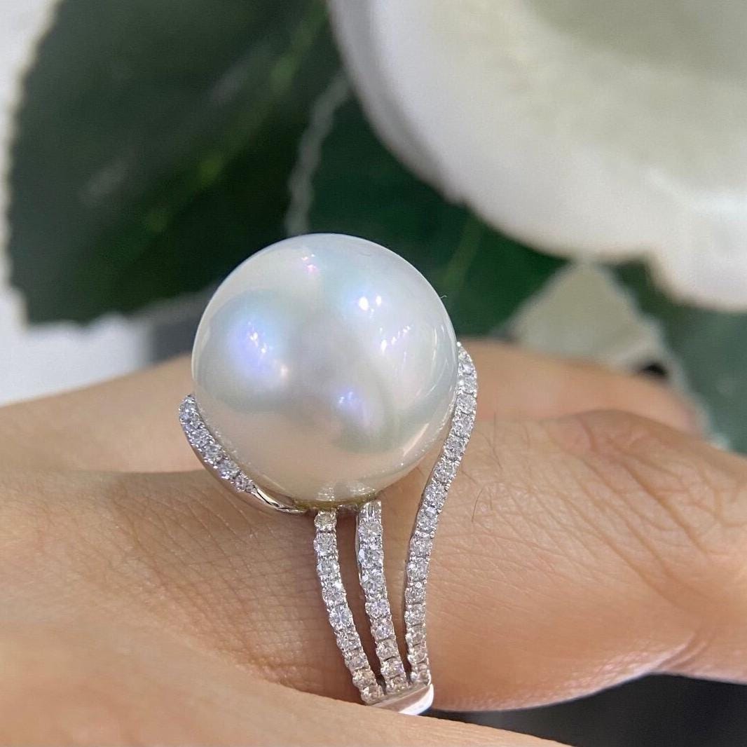 Woman is wearing a white gold diamond ring with a large center pearl (etsy image id: 6741495260)