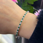 Woman wearing white gold alternating round cut diamond and round emerald half circle bangle. __etsy:6741597297