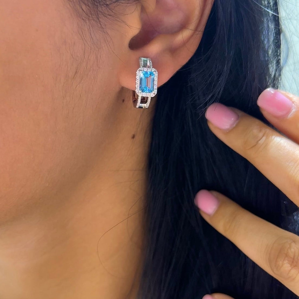 Girl wearing white gold blue topaz gemstone surrounded by diamonds huggie earring. (etsy image id: 6758205359)