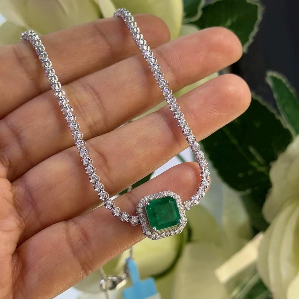 Woman holding white gold diamond tennis necklace with a cushion cut green emerald in a halo setting (etsy image id: 6761143799)