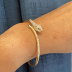 Woman wearing gold diamond panther bangle with the eyes of the panther in green emeralds (etsy image id: 6770648349)