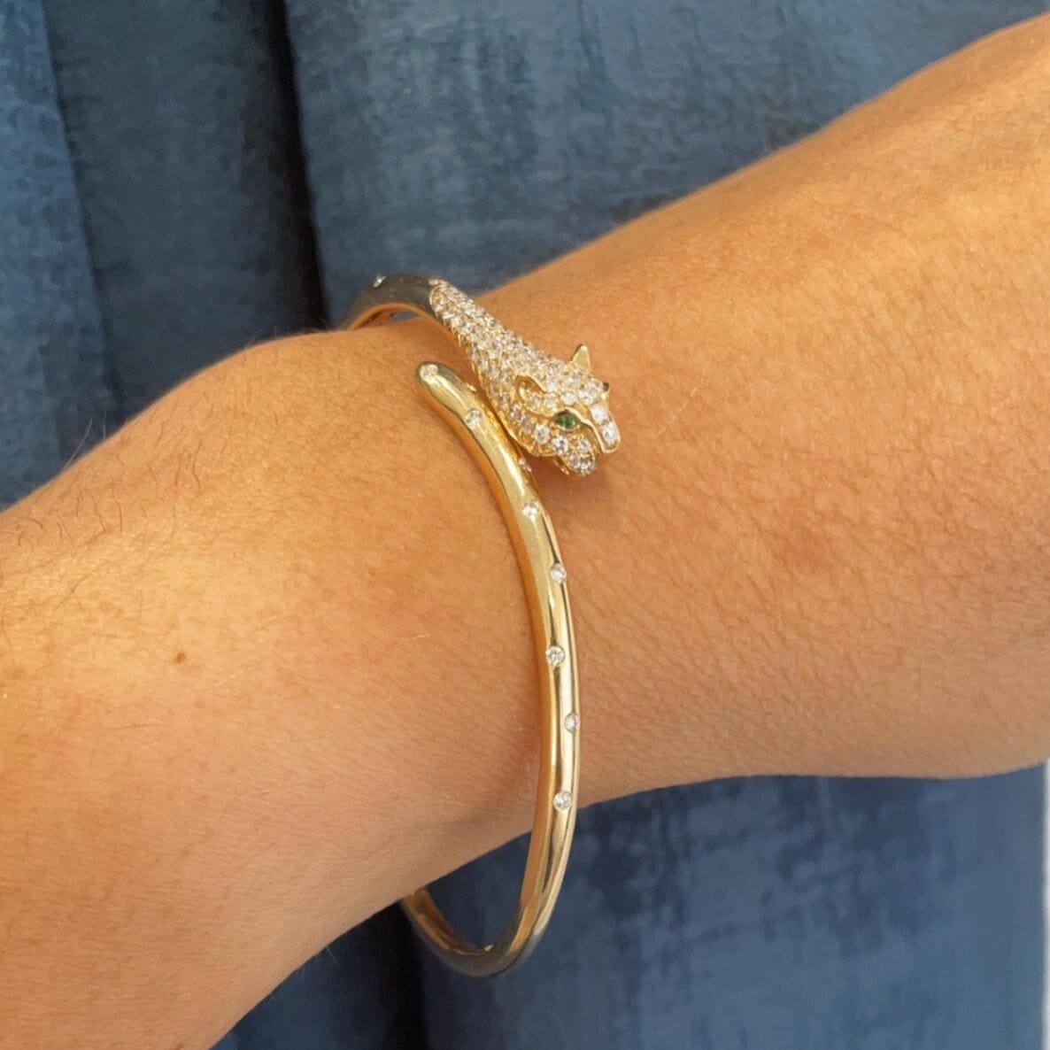 Woman wearing gold diamond panther bangle with the eyes of the panther in green emeralds (etsy image id: 6770648349)