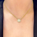 Woman wearing yellow gold chain with center pendant featuring single diamond surrounded by a halo of diamonds (etsy image id: 6770904385)