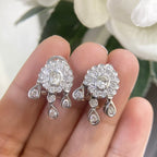 Woman holding white gold diamond cluster earrings with one center stone and multiple stones around it. (etsy image id: 6774554222)