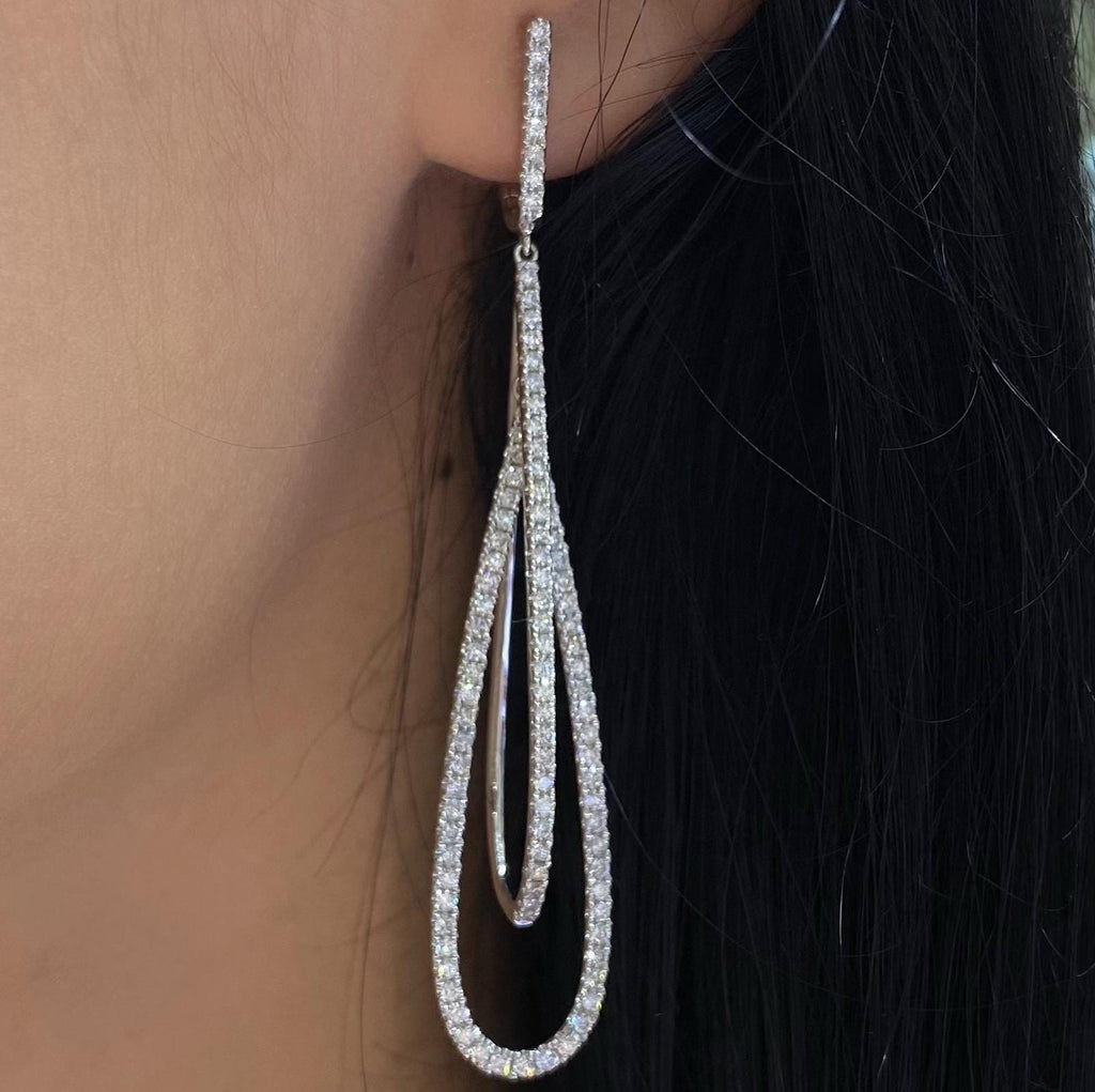 Woman wearing double tear drop elongated diamond earrings. (etsy image id: 6788592361)