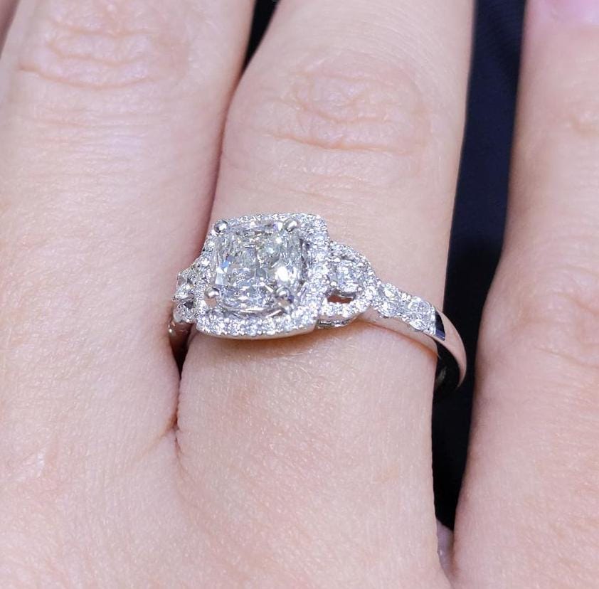 Woman wearing a clarity enhanced diamond engagement ring. Prong Halo setting with diamonds on the band. (etsy image id: 6791978375)