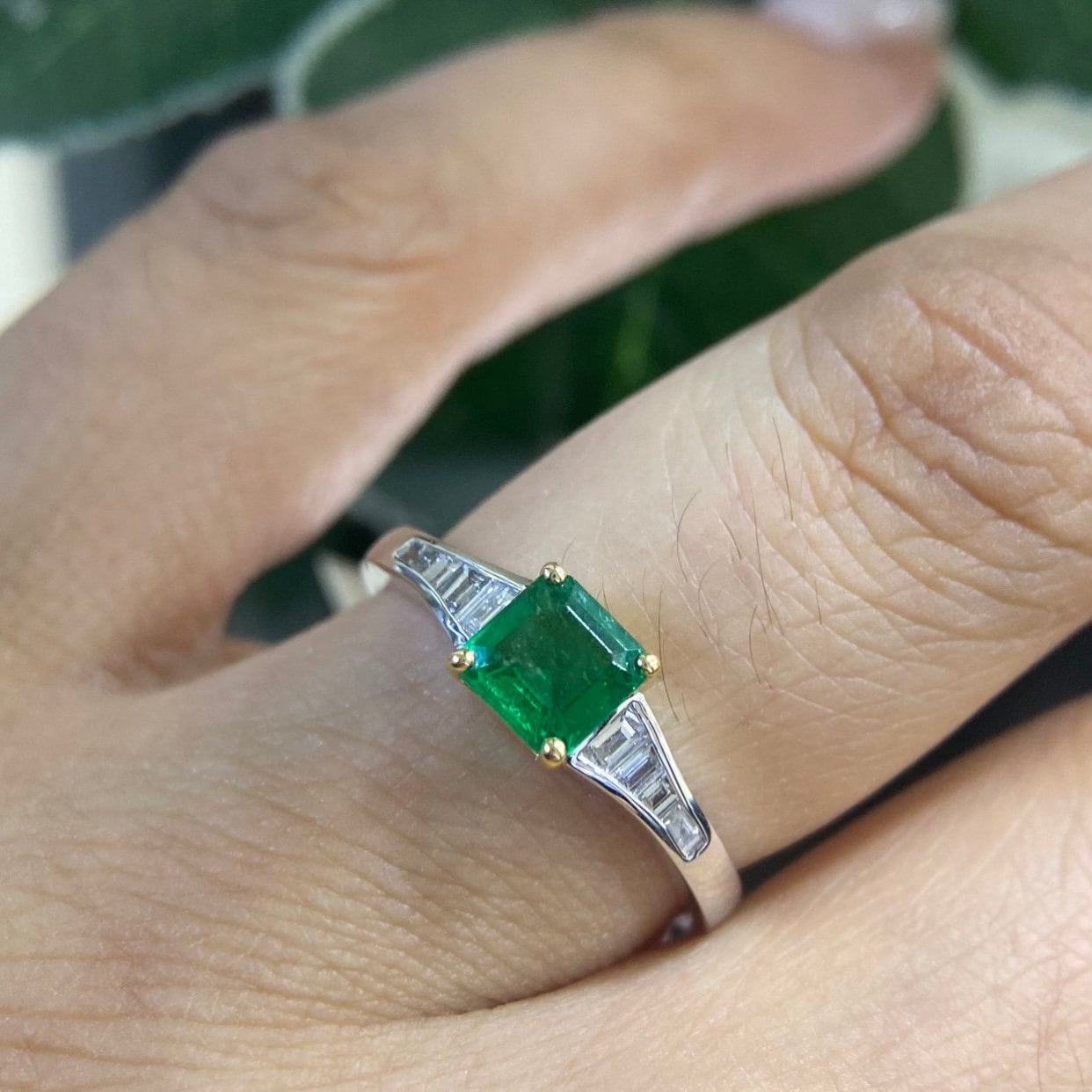 Woman wearing white gold ring with graduated baguettes on the sides. Center stone is a Ascher cut emerald set in yellow gold prongs. (etsy image id: 6794167651)