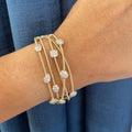 Woman wearing a yellow gold 5 row coil bracelet with clusters of diamonds. (etsy image id: 6845749612)